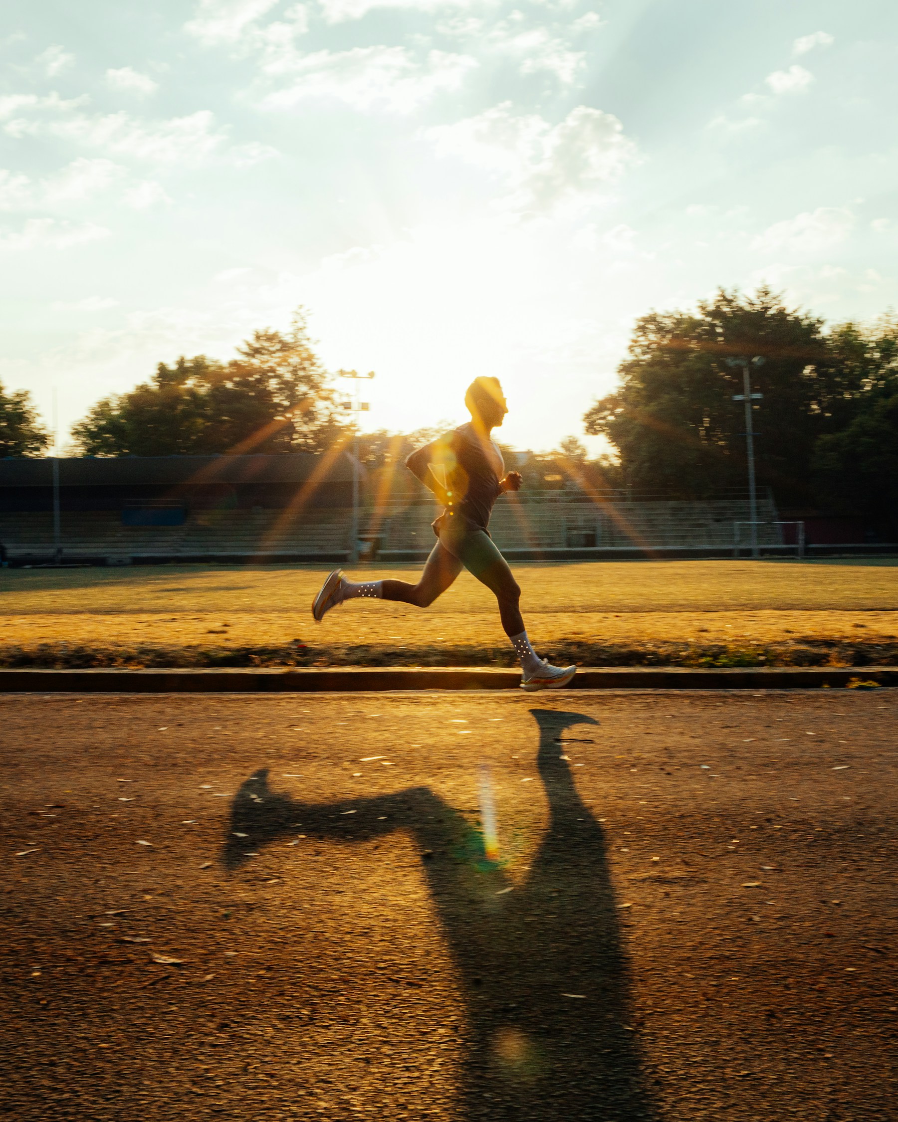 A runner sprints on a track in the golden sunlight